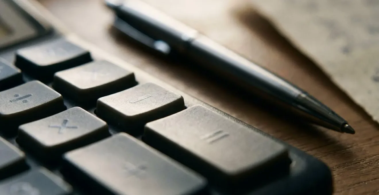 Calculatrice et documents financiers sur un bureau organisé montrant des calculs de remboursement d'assurance